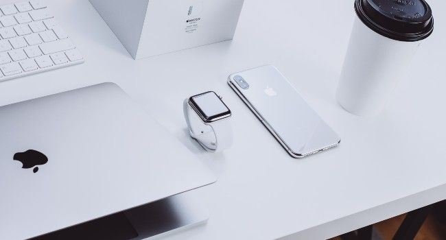 Ein Apple Laptop, Smartphone und weiteres Zubehör.