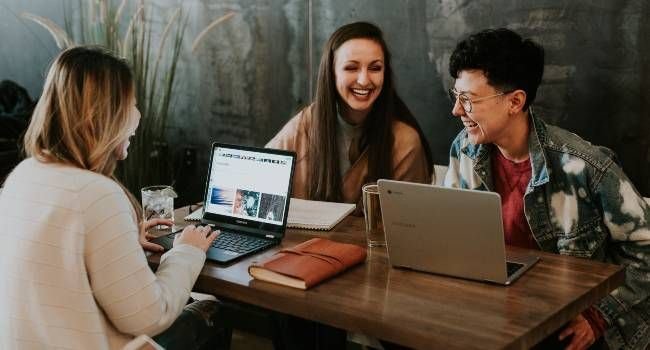 Drei Personen sitzen am Tisch und unterhalten sich