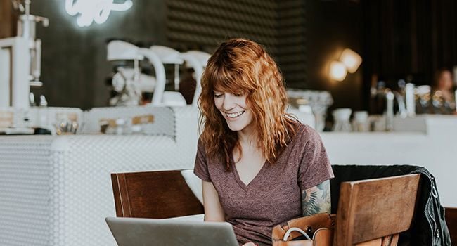 Eine Frau arbeitet am Laptop in einem Café.