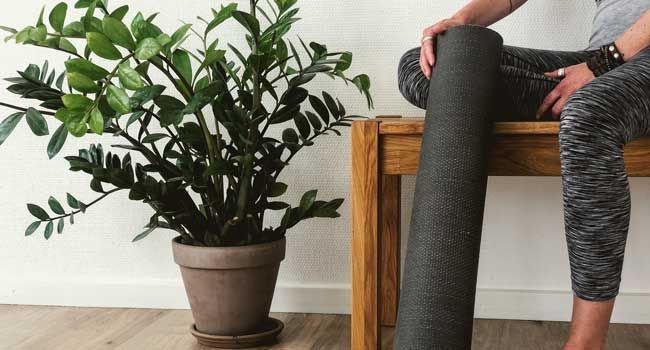 Person sitzt auf einer Bank und hält eine Yogamatte