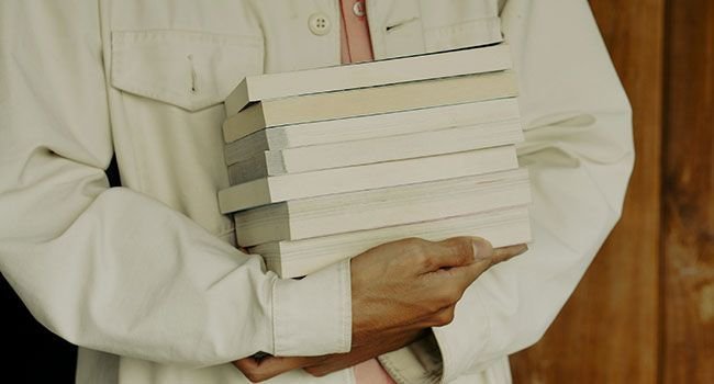 Eine Person mit einem Stapel Bücher in den Händen