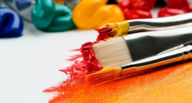 Ein Malpinsel und im Hintergrund halb ausgepresste Acyrlfarbe aus Tuben.