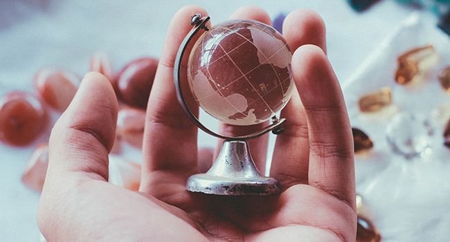 Ein kleiner Globus aus Glas in einer Hand