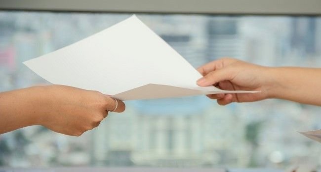 Die Abbildung zweier Hände bei der Überreichung eines Zettels.