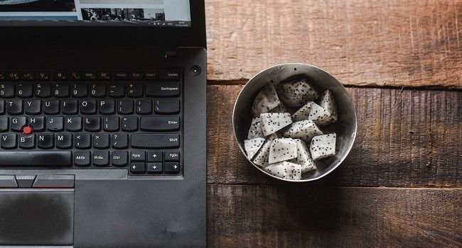 Ein Laptop und daneben eine Schüssel kleingeschnittener Obst