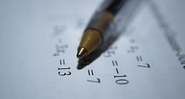 Ein Kugelschreiber auf einem Zettel mit mathematischen Aufgaben.