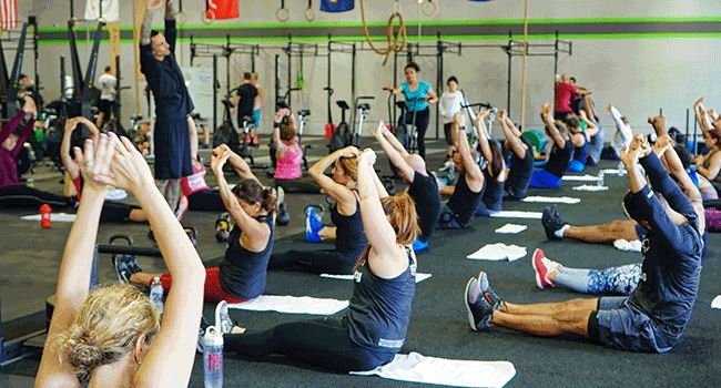 Mehrere Personen in einer Sporthalle beim Yoga.