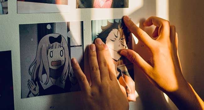 Hände einer Person steckt ein Bild mit einer Manga Zeichnung an eine Wand.
