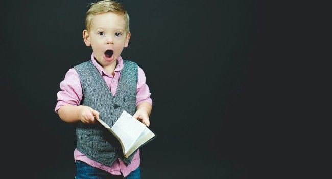 Ein Junge mit einem Buch in der Hand mit staunendem Blick