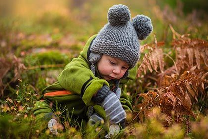 Photo by ???? Janko Ferlic on Unsplash Ein kleines Kind sitzt im Herbstlaub und spielt.